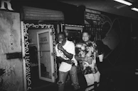 A local small business owner proudly standing in front of their shop, smiling with customers nearby.