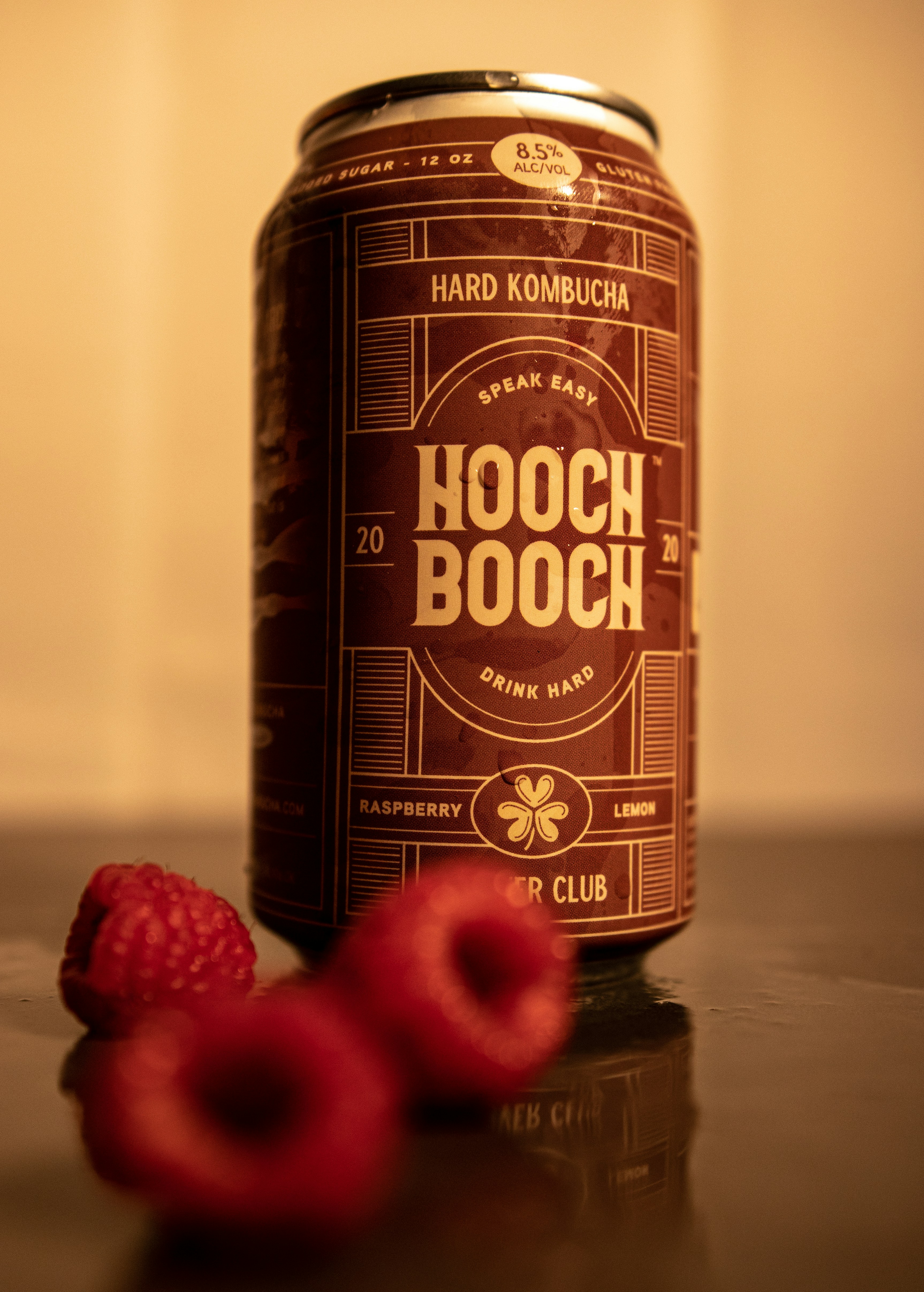 a can of hooch booch next to raspberries