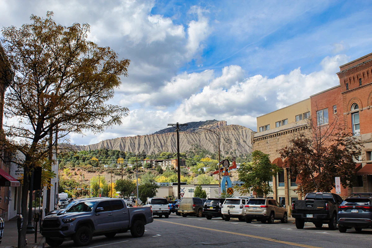 A street of brick buildings in Durango, with a pale cliff-banded mountain behind