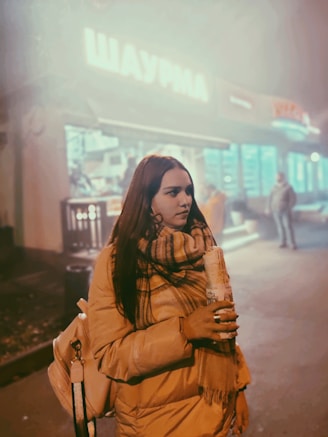 a woman walking down a street holding a drink