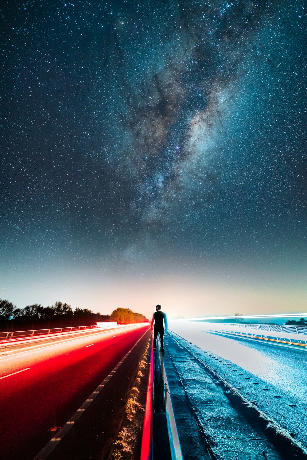 a person standing on the side of a road under a night sky