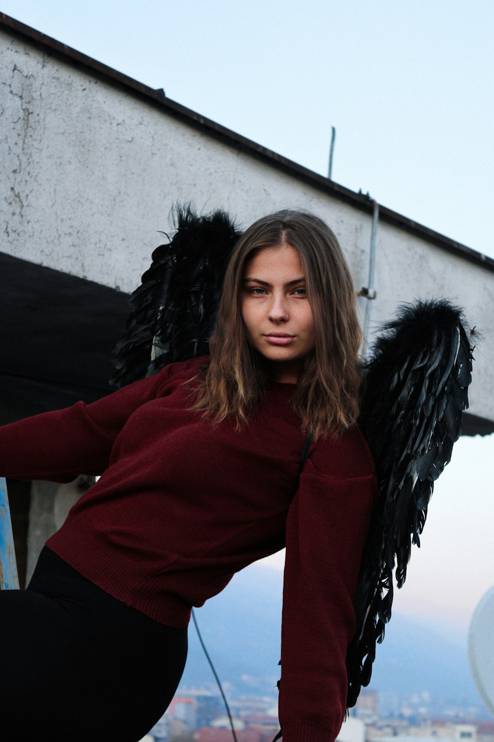 a woman in a red sweater and black angel wings