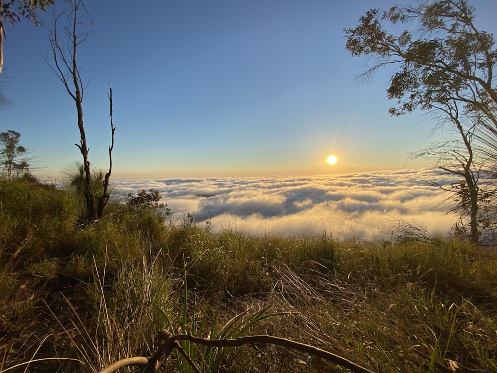 the sun is setting over the clouds in the mountains