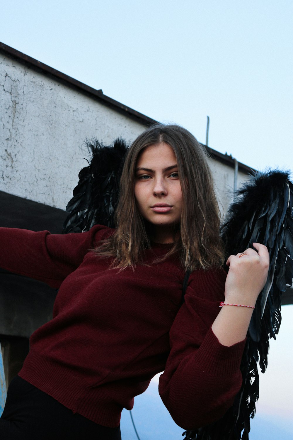 a woman in a red sweater holding a black angel wings