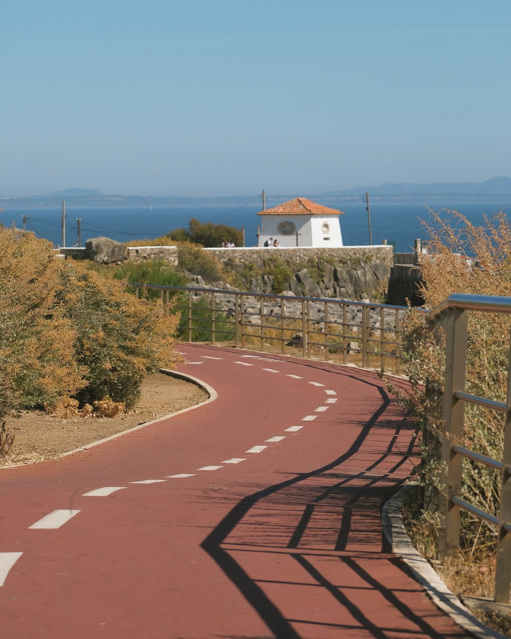 a winding road with a white house in the background