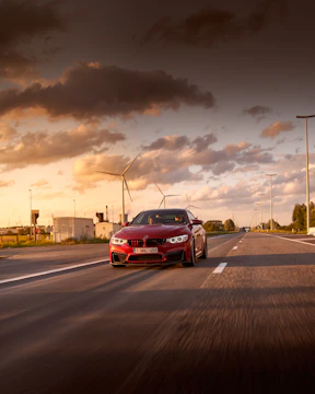Modified muscle car roaring down an open highway at sunset.