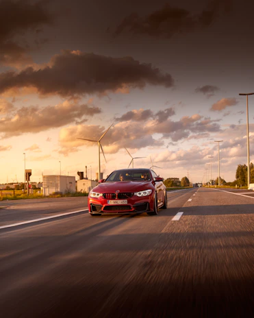 Dynamic shot of a red Dodge Charger speeding on an open highway at sunset.