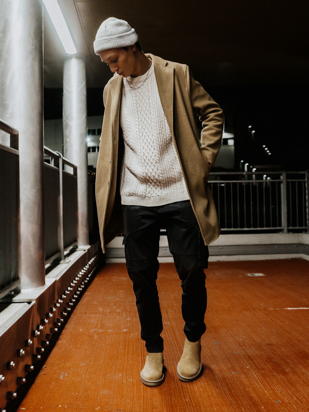 a man standing on a wooden floor wearing a coat