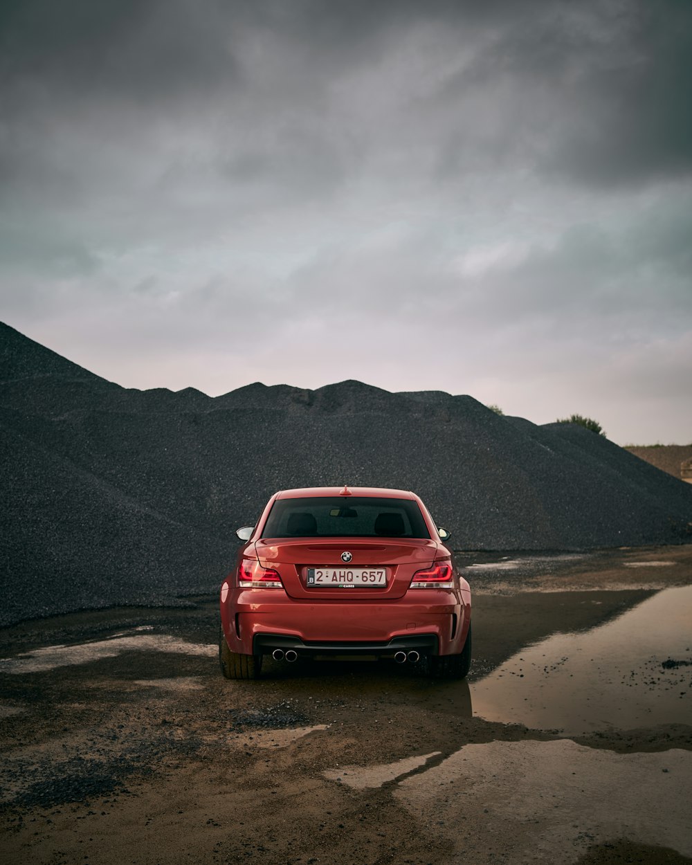 a red car parked in front of a mountain