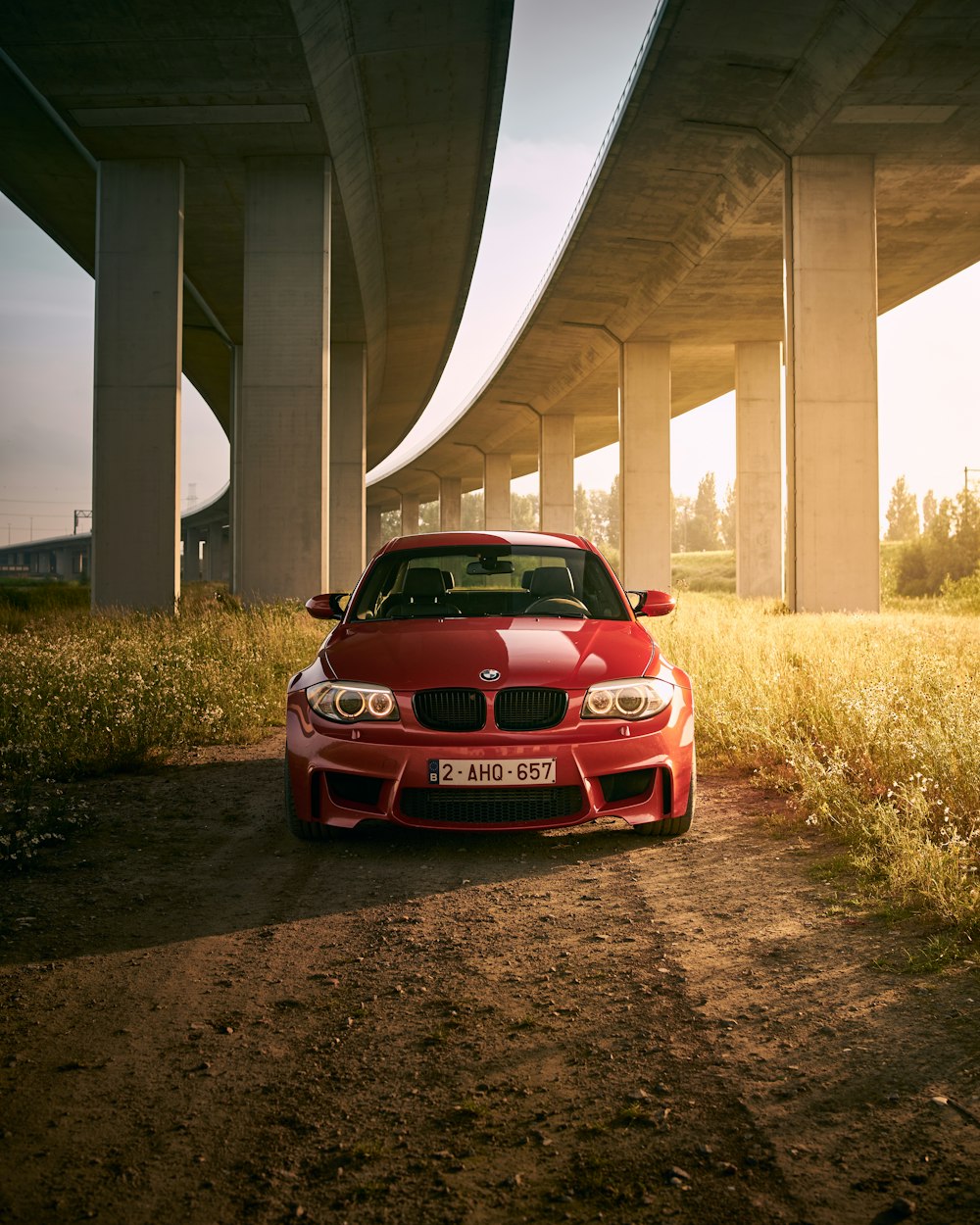 a red car is parked under a bridge