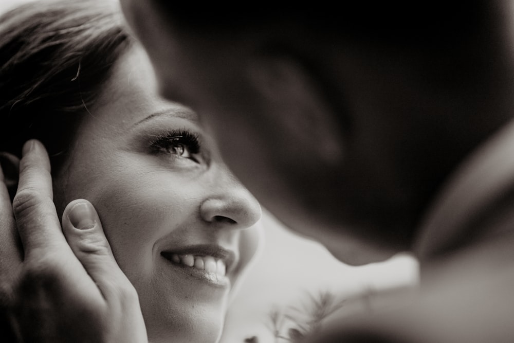 a woman smiles as she holds her hand to her ear