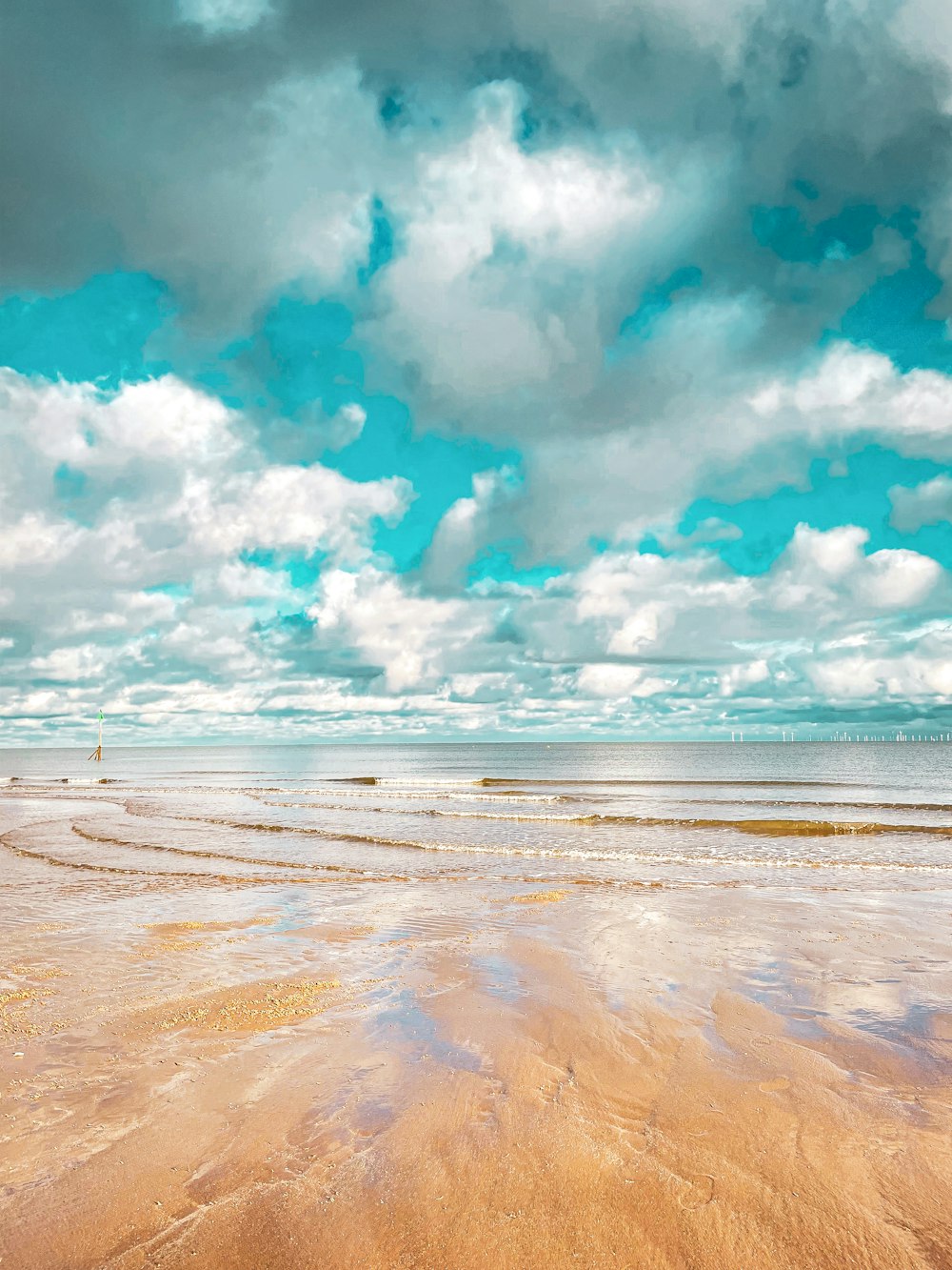 a sandy beach under a cloudy blue sky