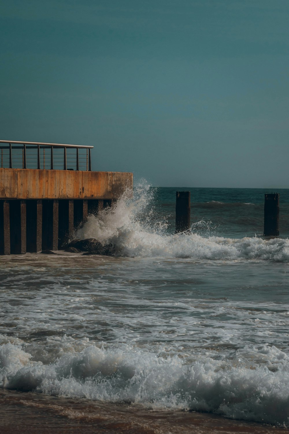 waves crashing into the shore of a pier