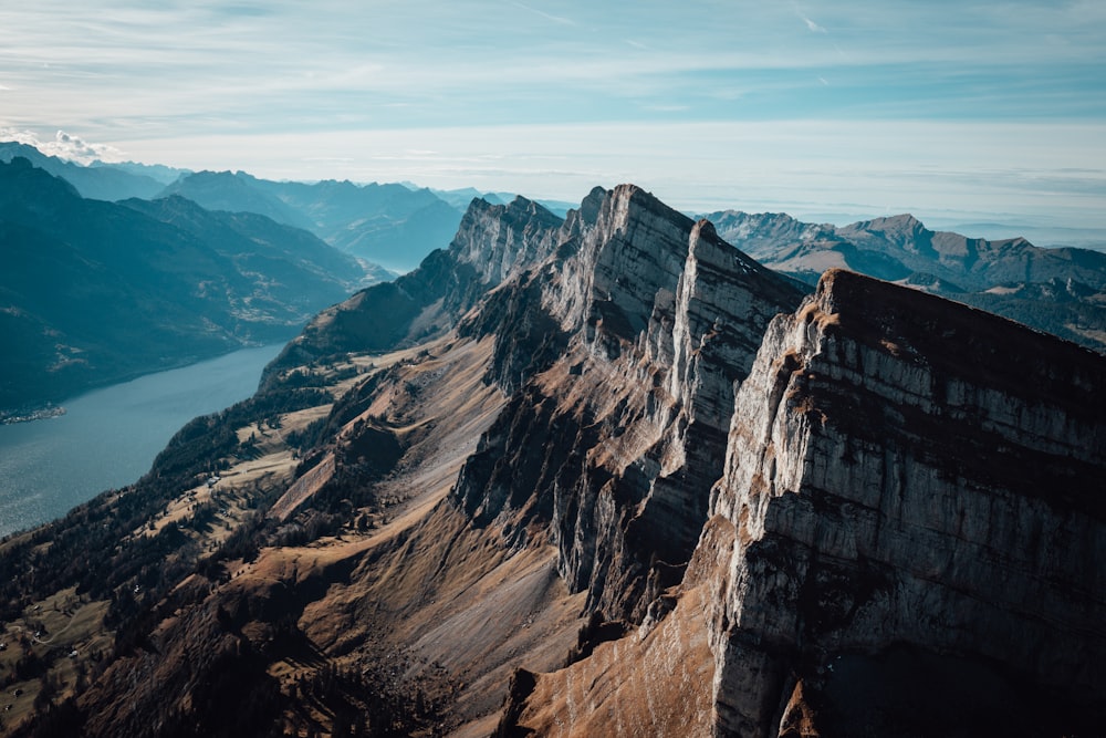 an aerial view of a mountain range with a body of water in the distance