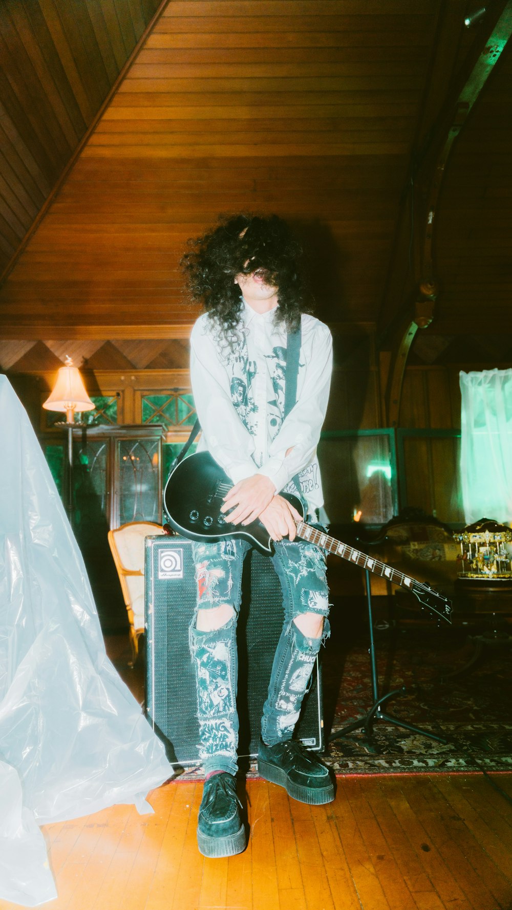 a man sitting on top of a guitar in a room