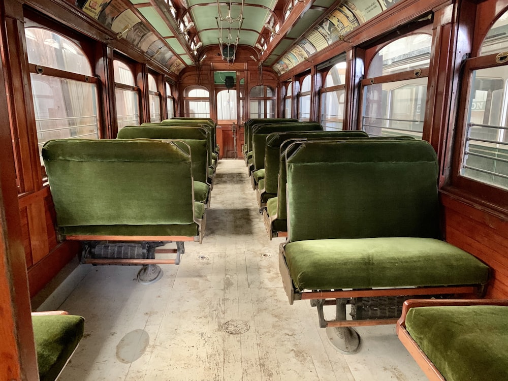 a row of green seats sitting inside of a train