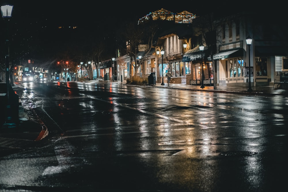 a wet city street at night with lights on