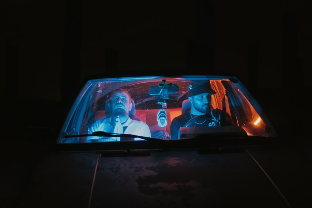 a couple of people sitting in a car in the dark