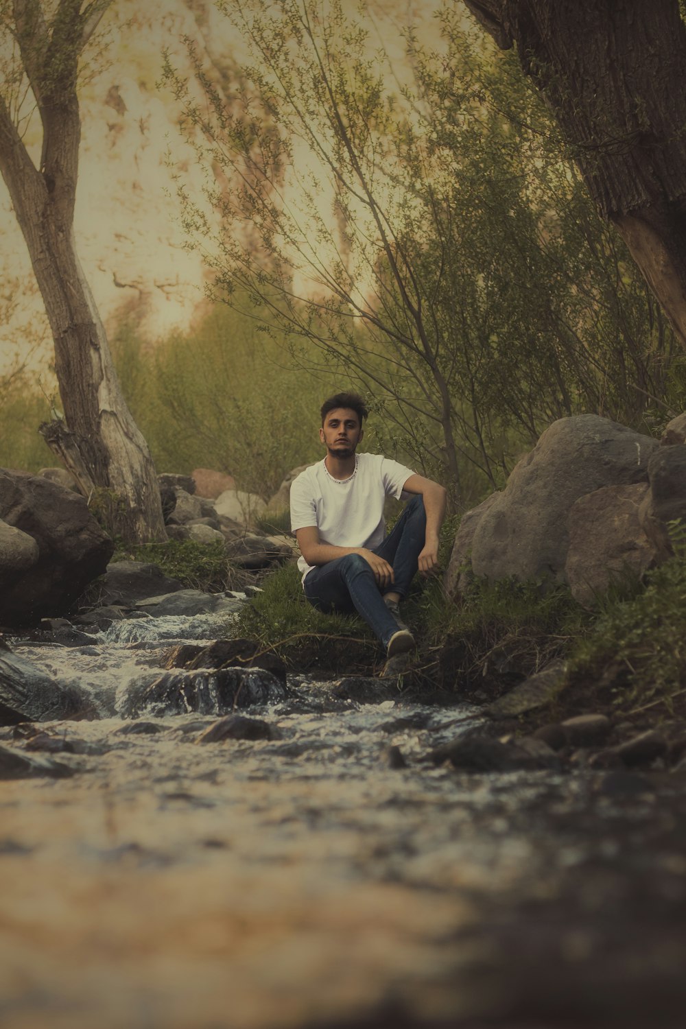 a man sitting on a rock next to a river
