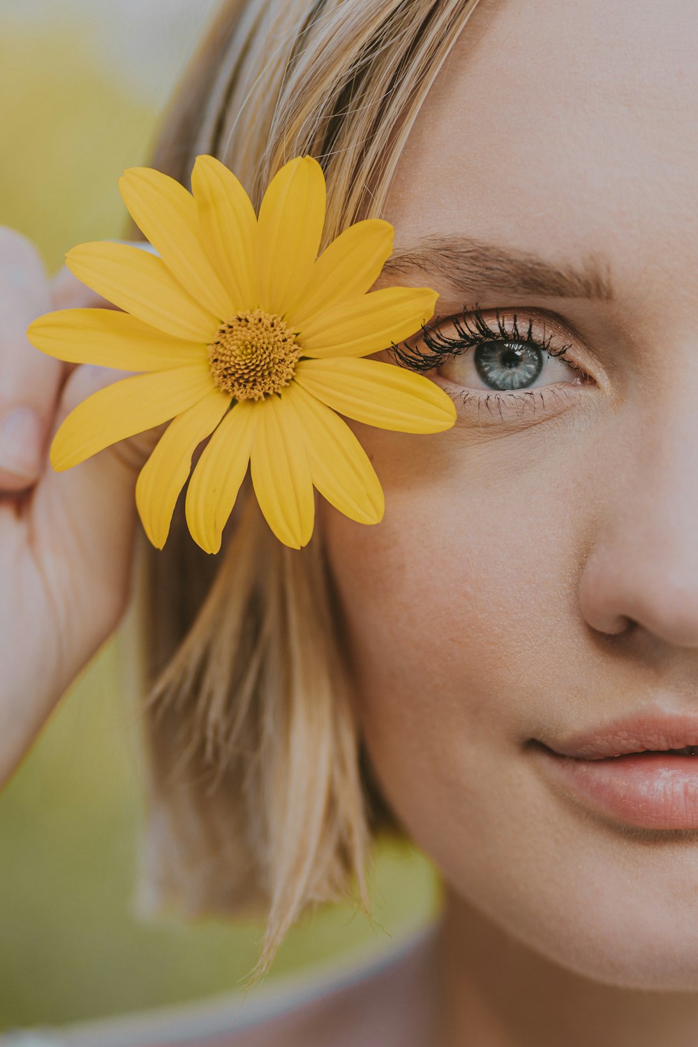 a woman holding a yellow flower up to her face