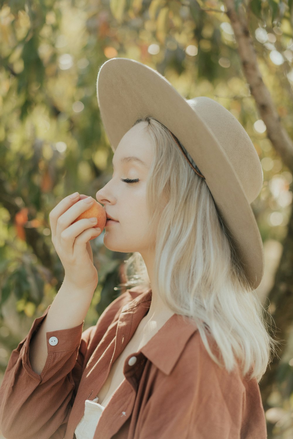 a woman in a hat is eating an apple