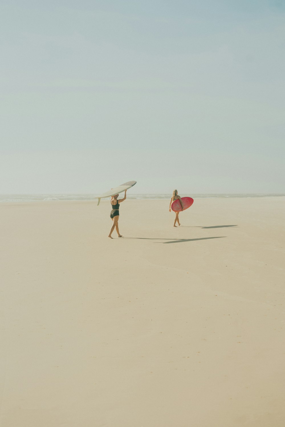 a couple of people walking across a sandy beach