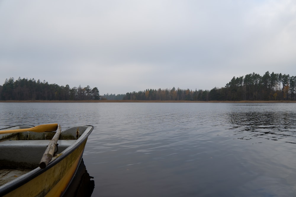 a yellow boat sitting on top of a lake next to a forest