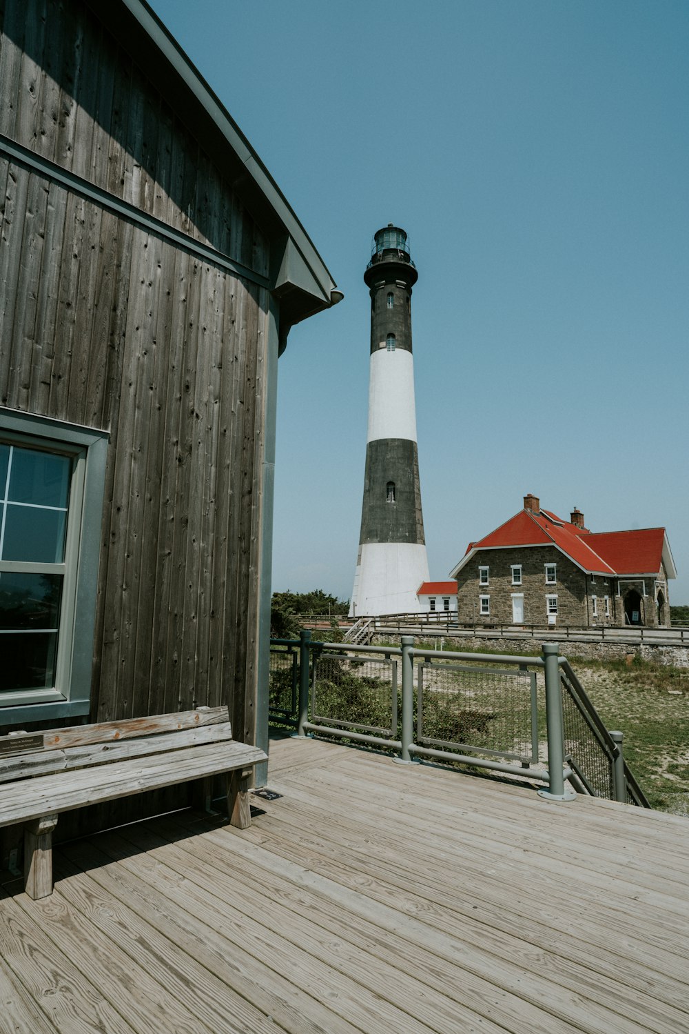 a wooden deck with a bench and a light house in the background