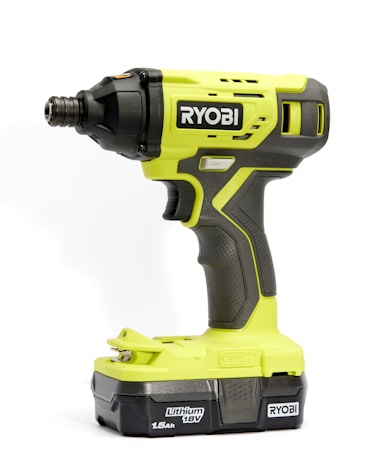 A bright green and black cordless power drill with the brand name 'Ryobi' prominently displayed. The drill features textured grips and buttons for operation, and the battery section is labeled 'Lithium 18V 1.5Ah'.
