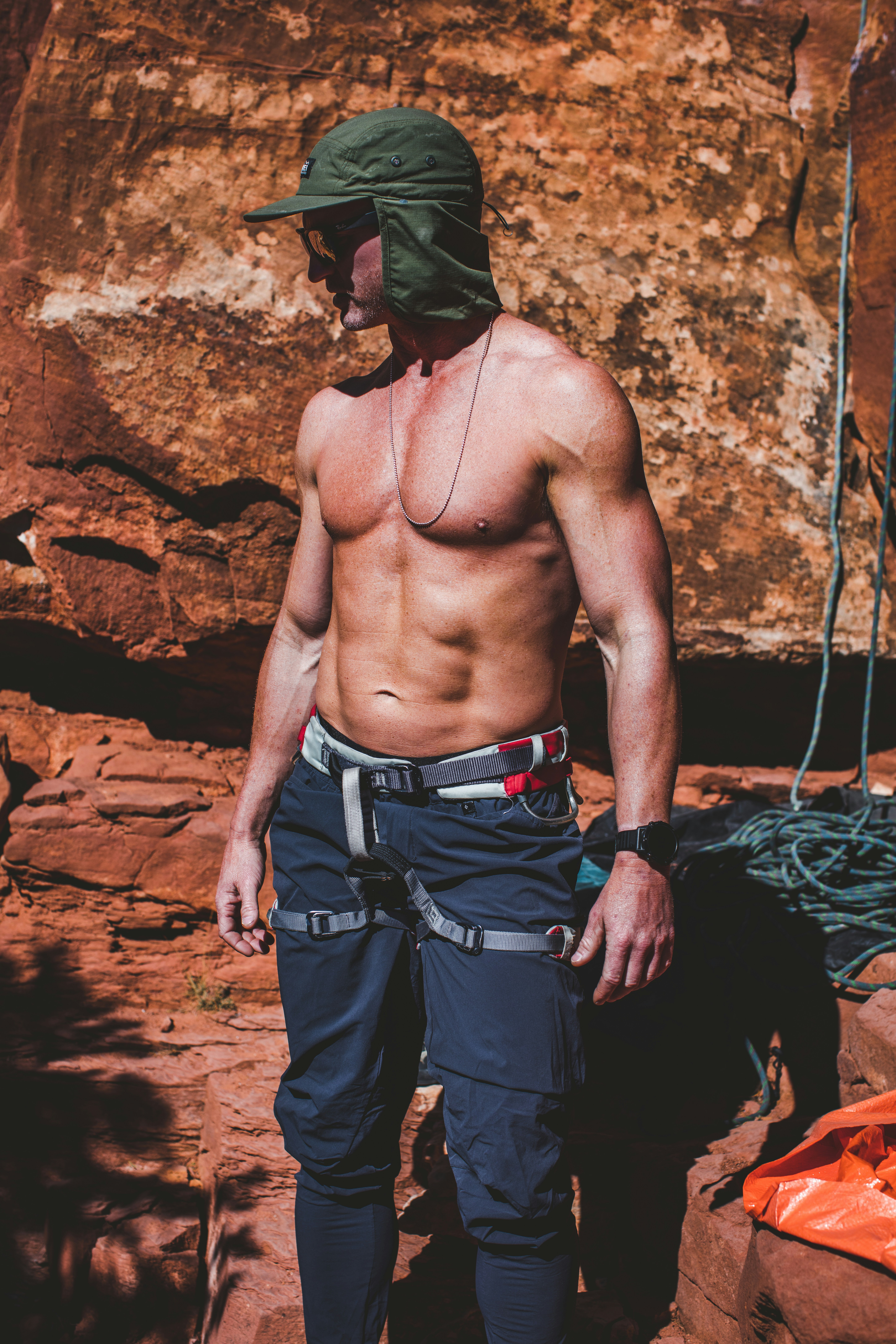 a man with no shirt standing in front of a rock
