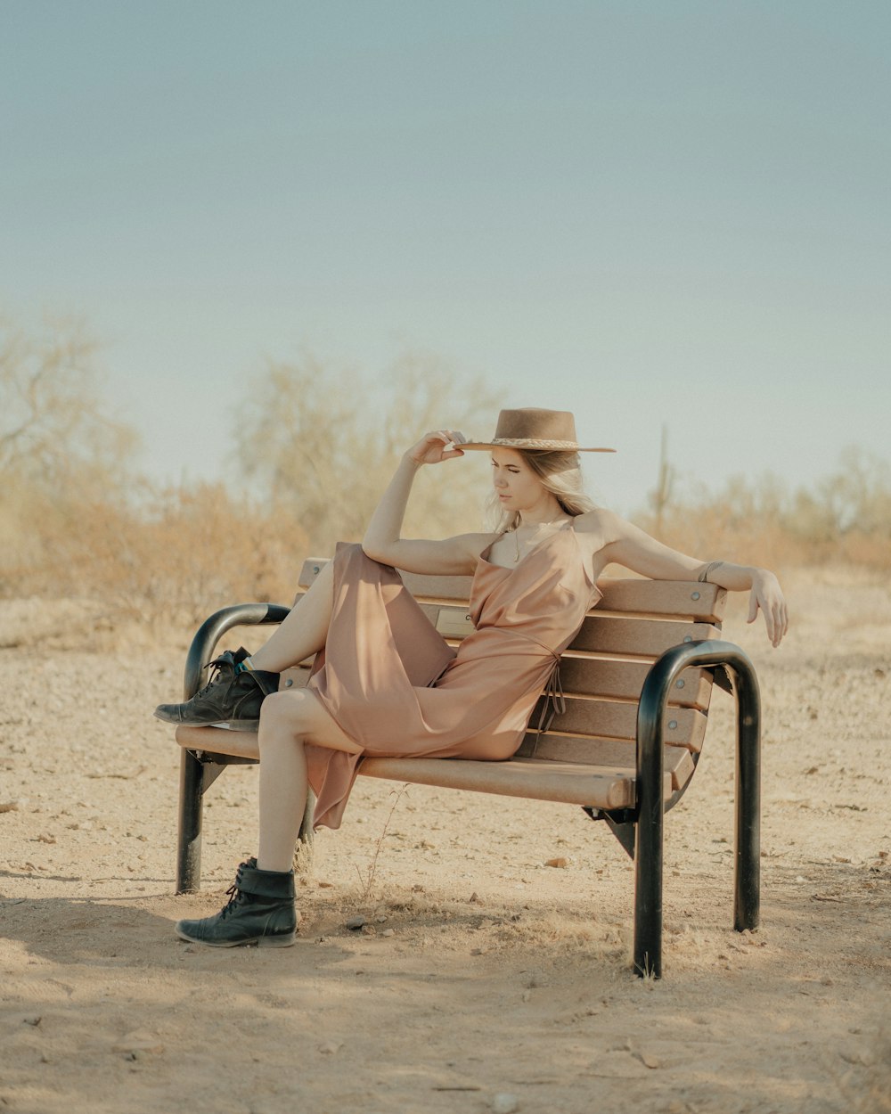 a woman sitting on a bench in the desert