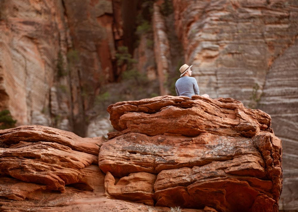 a person sitting on top of a large rock