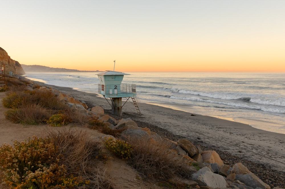 a lifeguard tower on the beach at sunset