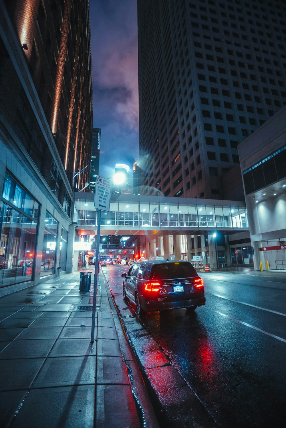 a city street at night with cars parked on the side of the road