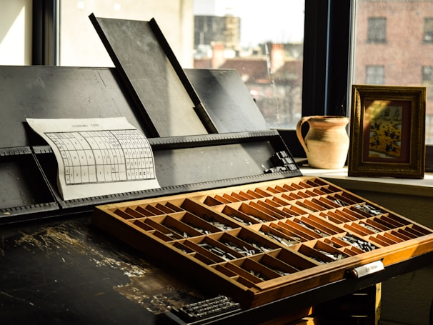 Antique typesetting tools resting beside an open specimen book.