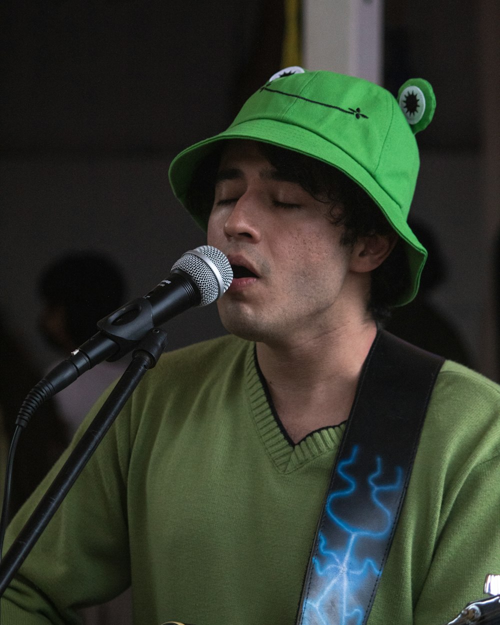 a man with a green hat playing a guitar