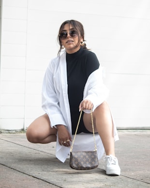 a woman sitting on the ground holding a purse