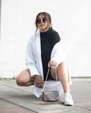 a woman sitting on the ground holding a purse