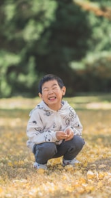 a young boy sitting on the ground laughing