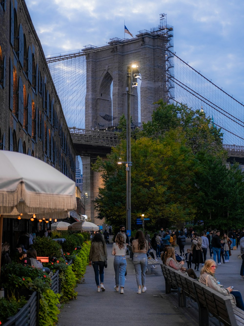 a group of people walking down a sidewalk next to a bridge