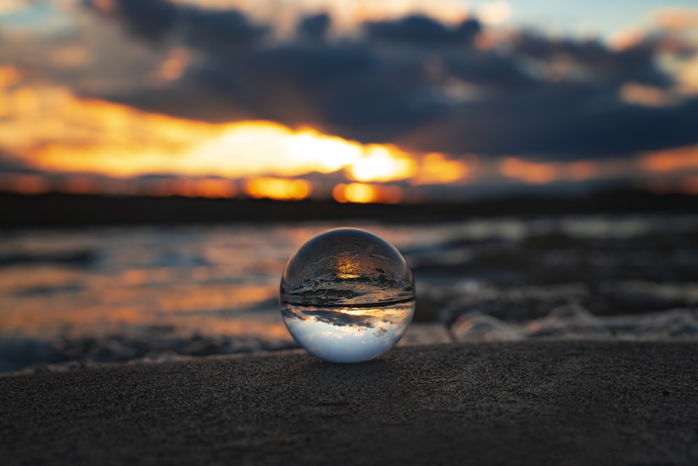 a glass ball sitting on top of a sandy beach