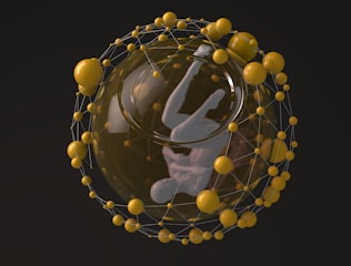 A humanoid figure suspended in a fetal position within a transparent sphere, surrounded by a network of interconnected yellow spheres. The structure resembles a scientific or futuristic representation.