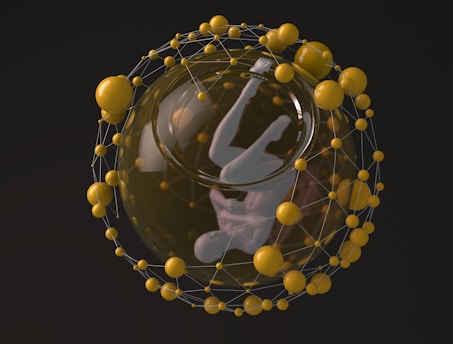 A humanoid figure suspended in a fetal position within a transparent sphere, surrounded by a network of interconnected yellow spheres. The structure resembles a scientific or futuristic representation.