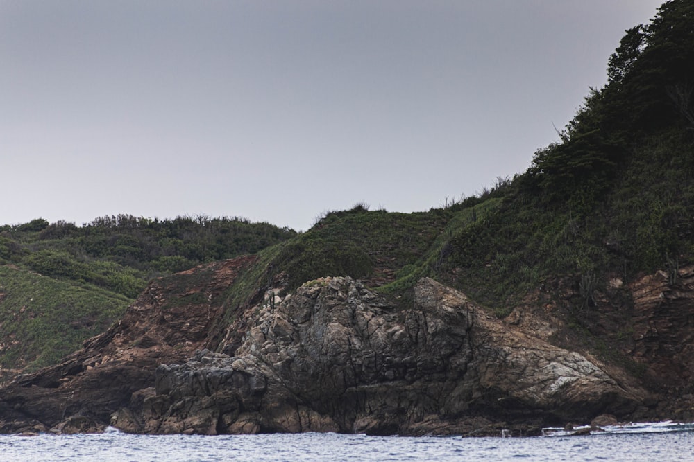 a large body of water next to a lush green hillside