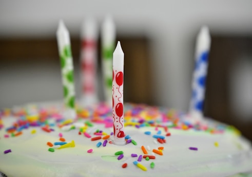 A vibrant birthday cake with colorful candles and confetti around it.