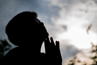 A silhouette of a person praying before a workout in a sunlit gym.