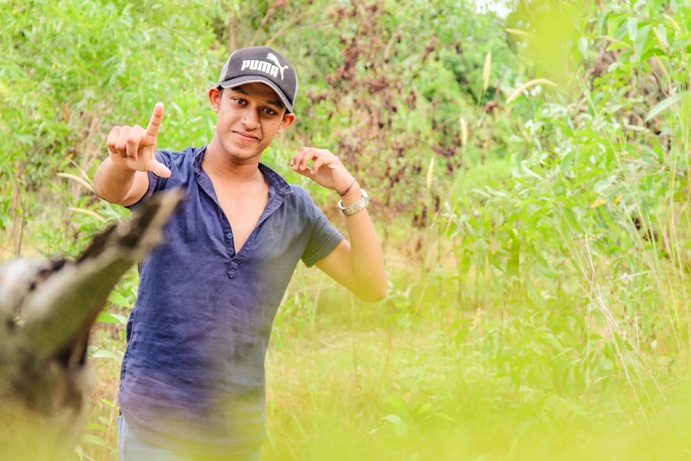 a man in a baseball cap pointing at the camera