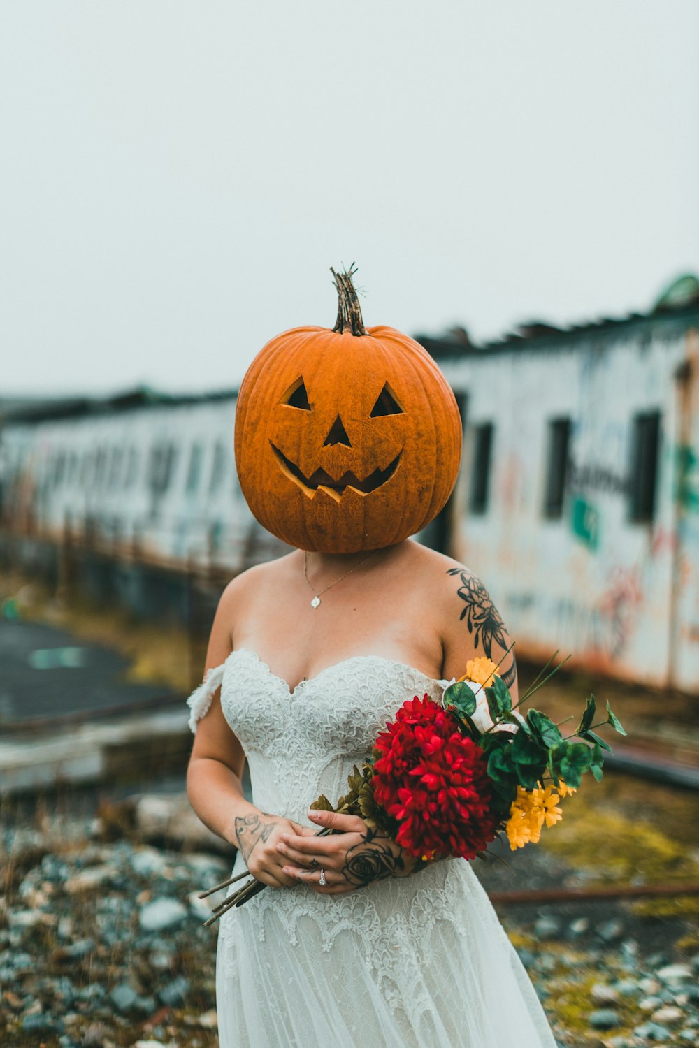 a woman in a wedding dress with a pumpkin on her head