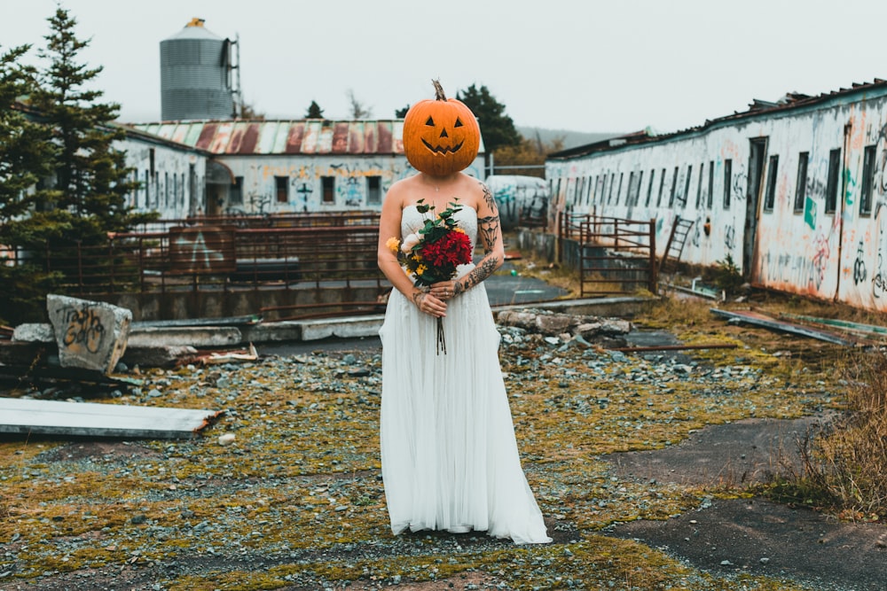 a woman in a white dress with a pumpkin head on her head