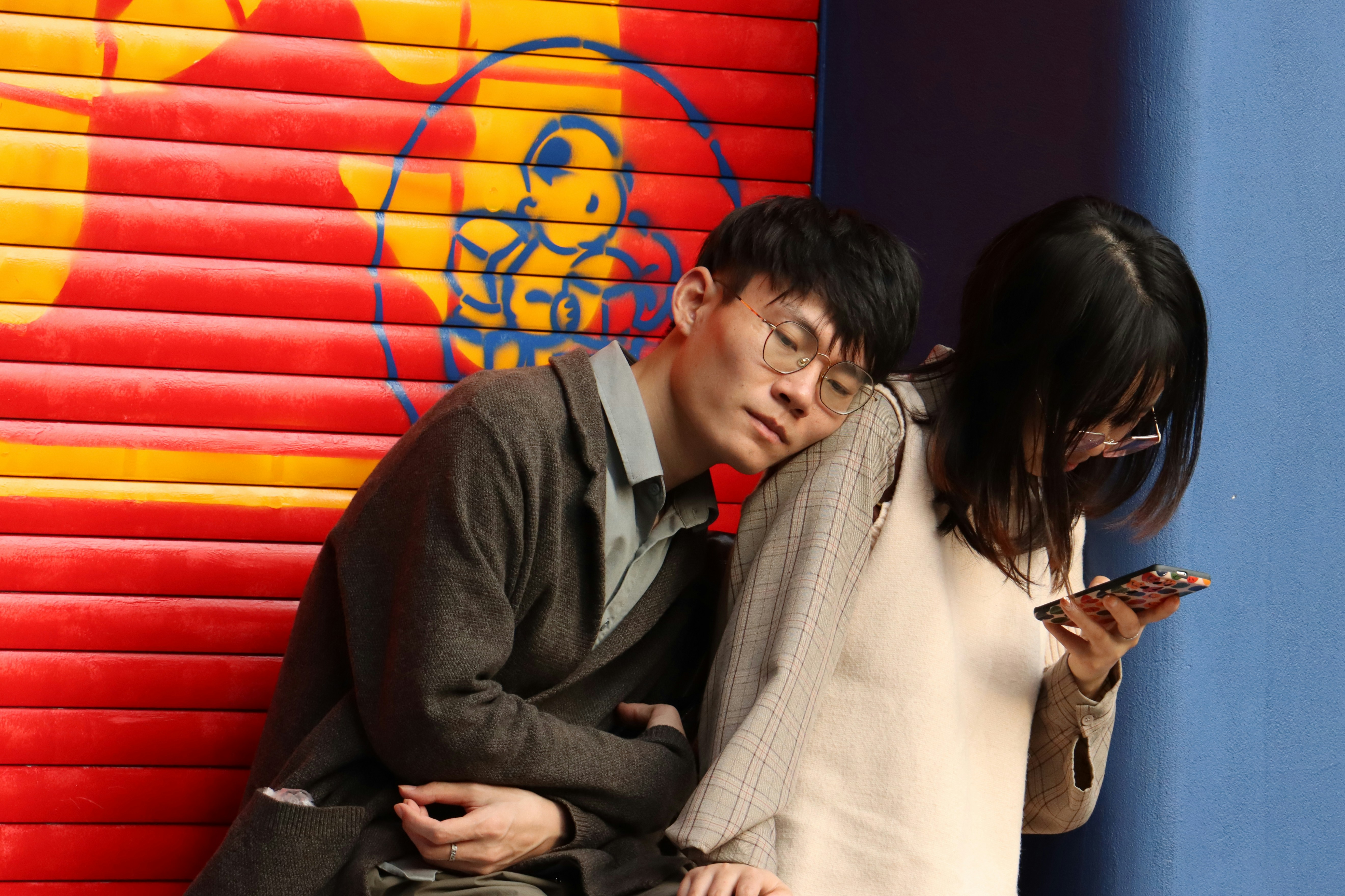 a man and a woman leaning against a wall